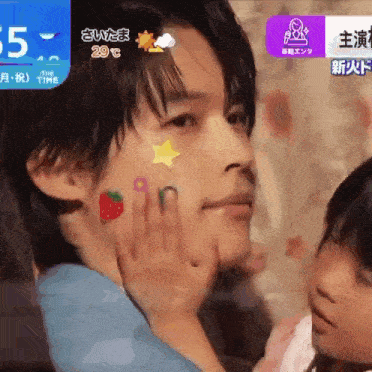 a man with stickers on his face is being held by a little girl and the time is 29