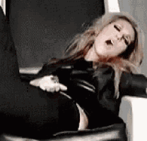 a woman in a black leather jacket is laying on a chair with her mouth open .