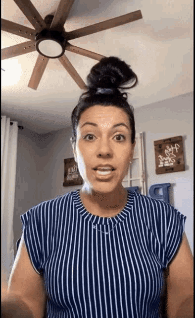 a woman in a blue and white striped shirt has a tattoo on her neck