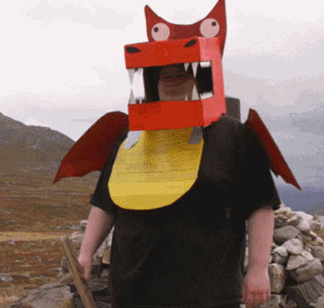 a person wearing a cardboard dragon costume holds a stick