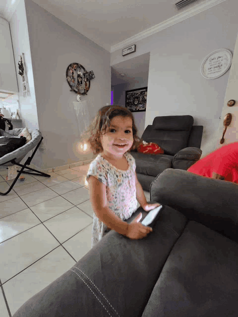 a little girl is sitting on a couch in a living room with a sign on the wall that says " i love you "