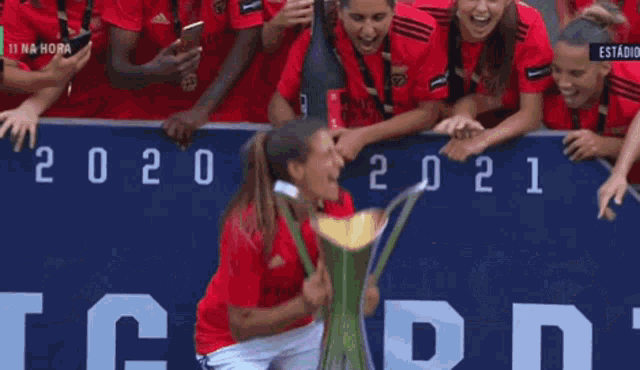 a blurred image of a group of people holding a trophy with the words 11 na hora in the corner