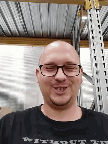 a bald man wearing glasses and a shirt that says without