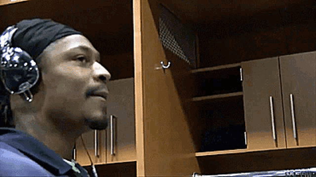 a man wearing headphones and a headband looks up at something in a closet