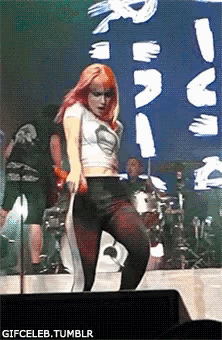 a woman with red hair is dancing on a stage in front of a sign that says gifceleb.tumblr