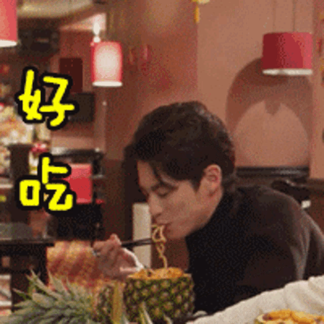 a man in a black turtleneck is eating noodles from a pineapple