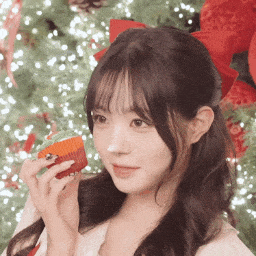 a girl with a red bow in her hair is holding a cupcake with green frosting