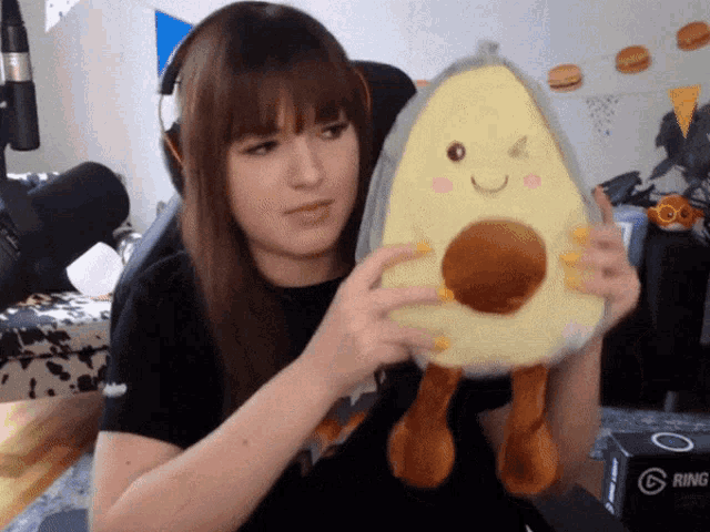 a woman is holding a stuffed avocado in front of a box that says ring