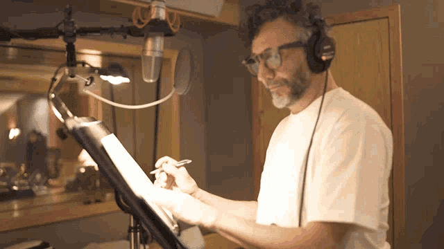 a man wearing headphones and glasses is reading a script