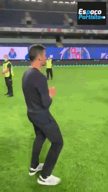 a man is dancing on a soccer field with a sign that says espaco portista
