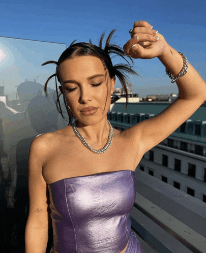 a woman wearing a purple strapless top and a silver chain necklace