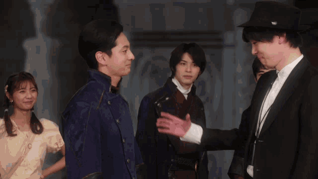 a man in a tuxedo shakes hands with another man in a purple jacket