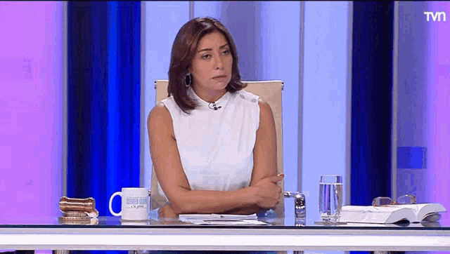 a woman sits at a desk in front of a tv screen that says ' tvn ' on it