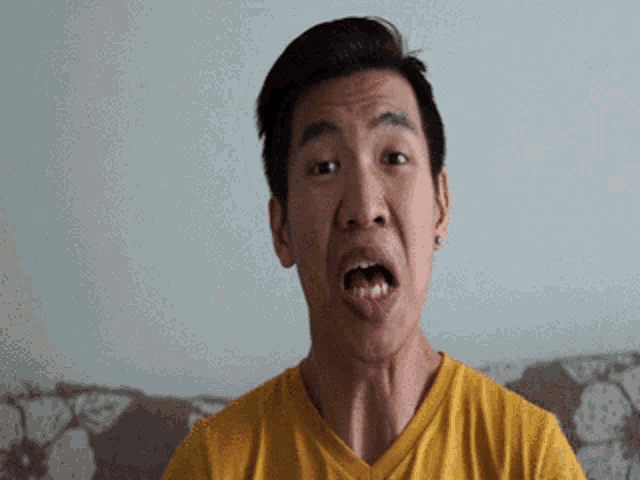a man in a yellow shirt is making a face
