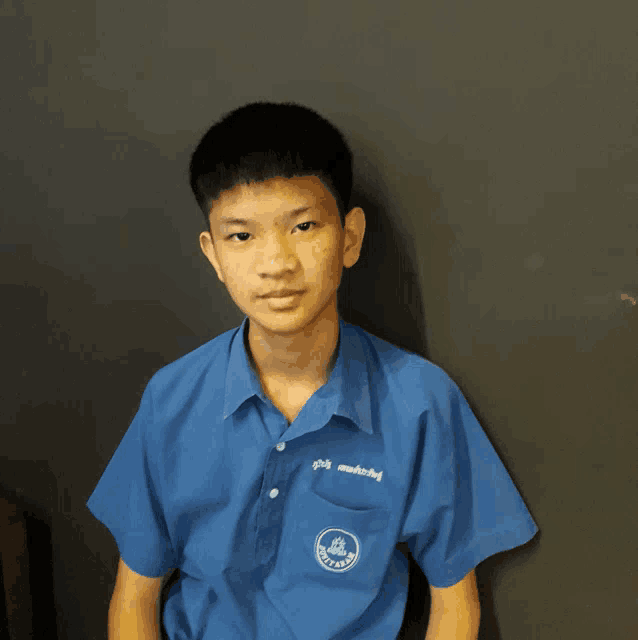 a young boy wearing a blue shirt with the word thailand on the pocket