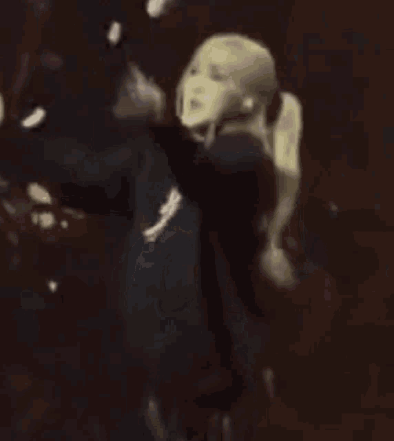 a woman is dancing on a stage in a dark room with a bunch of confetti falling around her .