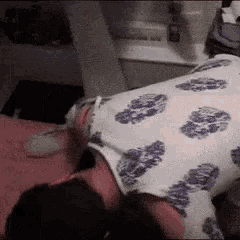 a person is laying on their back on a bed with a purple and white blanket .