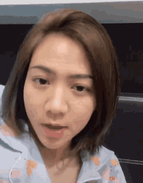 a woman with short hair is making a funny face while wearing a blue pajama top .