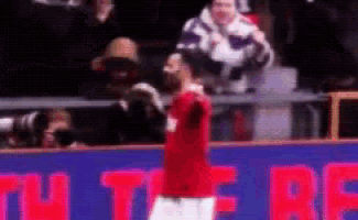 a man in a red shirt is standing in front of a sign that says ' u ' on it