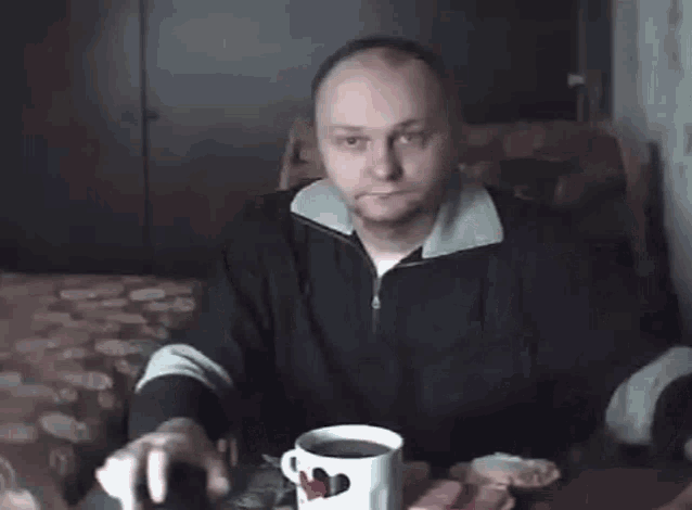 a man sits at a table with a cup of coffee and a piece of grapefruit