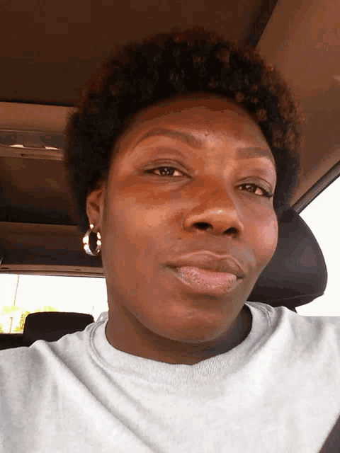 a woman in a car wearing hoop earrings