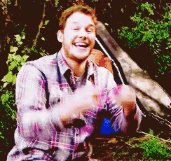 a man in a plaid shirt is sitting in the woods with his arms outstretched