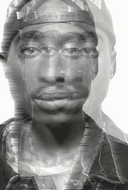 a black and white photo of a man with a hat and a necklace with the letter l on it