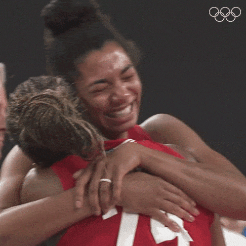 a woman in a red shirt with the number 7 on it hugging another woman