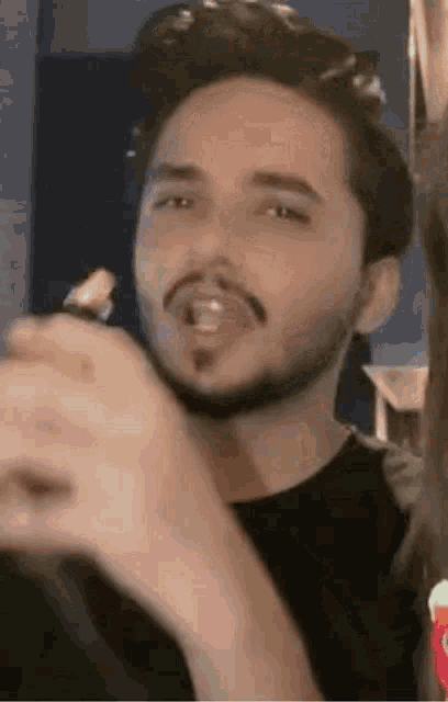 a man with a beard is sticking his tongue out at the camera .