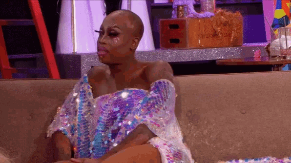 a woman is sitting on a couch wearing a sequined dress