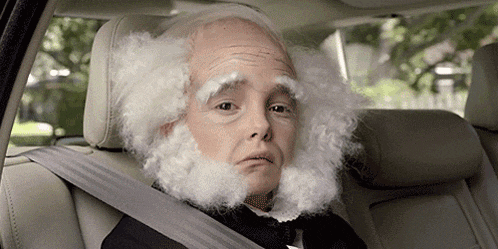 a man with white hair and a beard is wearing a seat belt in a car