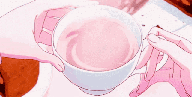 a person is holding a cup of pink liquid in their hand .