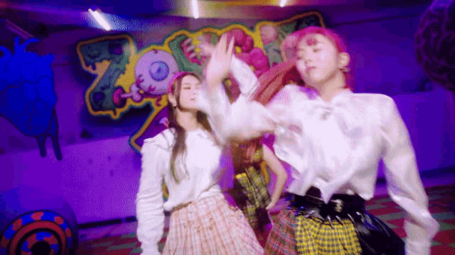 a group of young women are dancing in front of a purple wall with a heart on it