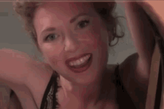 a woman in a black bra is smiling with her arm in the air