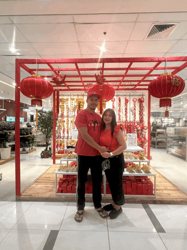 a man and woman are posing for a picture in front of a display of chinese lanterns