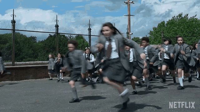 a group of children in school uniforms are running down a street with netflix written on the bottom