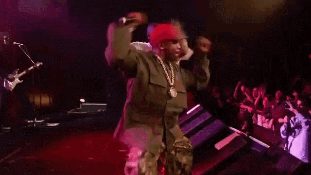 a man in a red hat is dancing on stage
