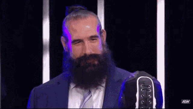 a man with a beard is standing in front of a microphone in a suit .