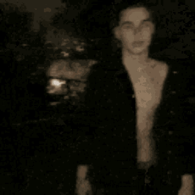 a man without a shirt is standing in a dark room