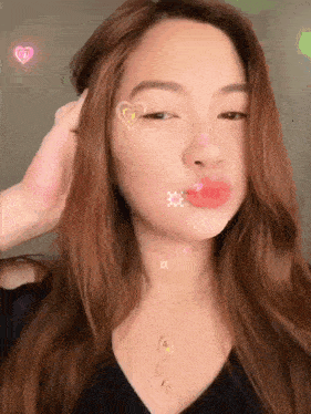 a woman with hearts on her face is wearing a black shirt and a gold necklace .