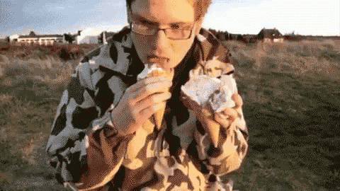 a man in a camo jacket is eating a sandwich .