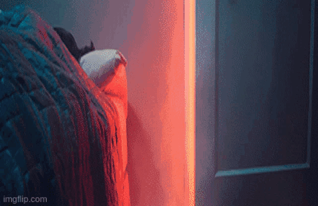 a person is sleeping in a bed with a red light behind them