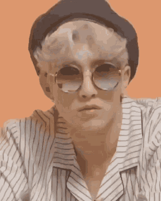 a young man wearing a hat and sunglasses is making a funny face .