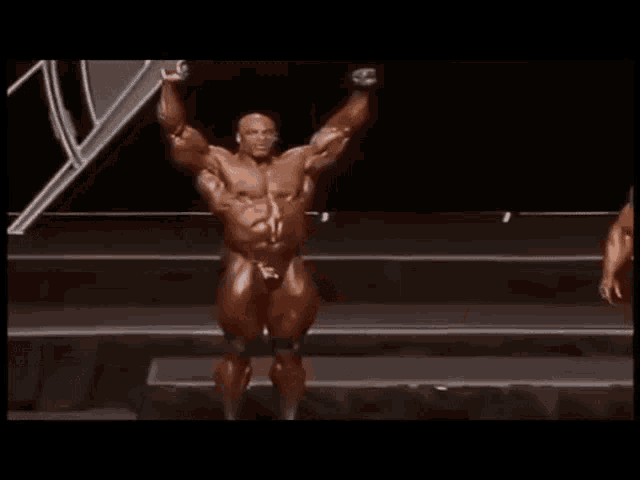 a muscular man in a bikini is standing on a stage in a bodybuilder 's pose .