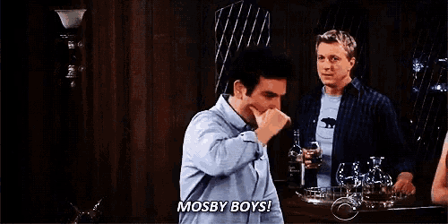 a man is holding his nose and saying mosby boys while standing in a bar .