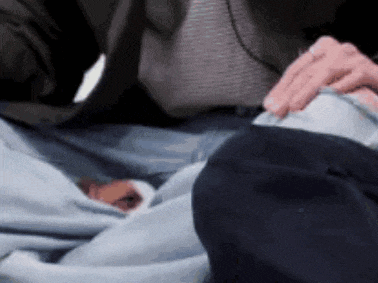 a man in a suit is holding a baby 's hand while laying on a bed .