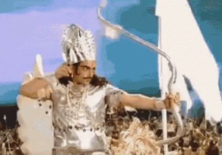 a man in a silver costume is holding a bow and arrow while wearing a crown .