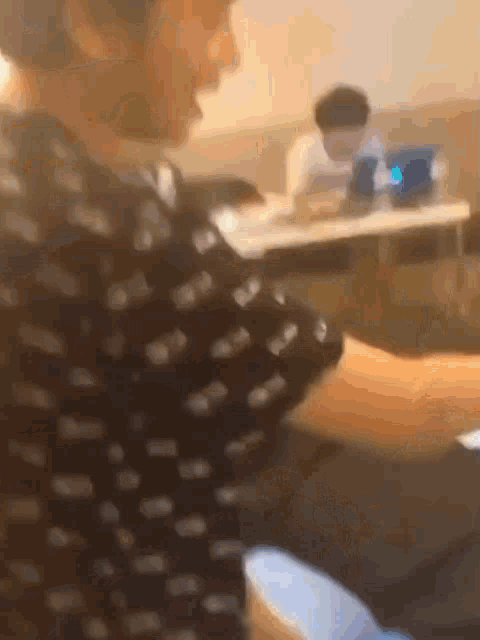 a man in a polka dot shirt is sitting at a table in a room with other people .