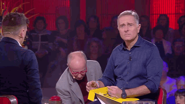 a man in a blue shirt is holding a yellow box that says ' s ' on it