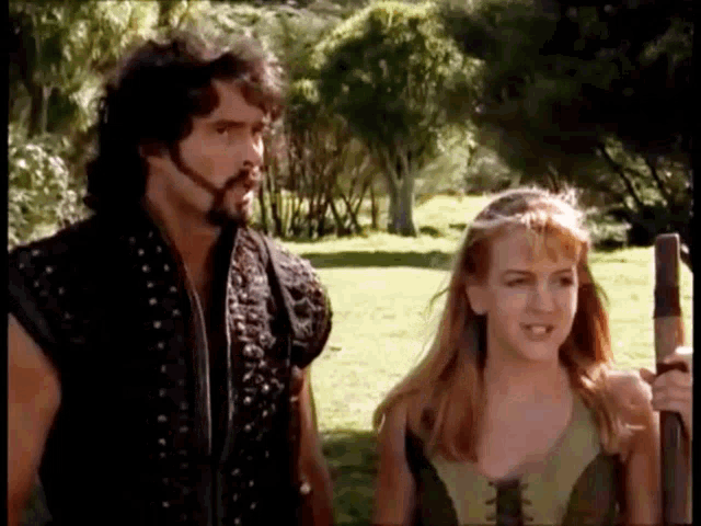 a man and a woman are standing next to each other in a grassy field